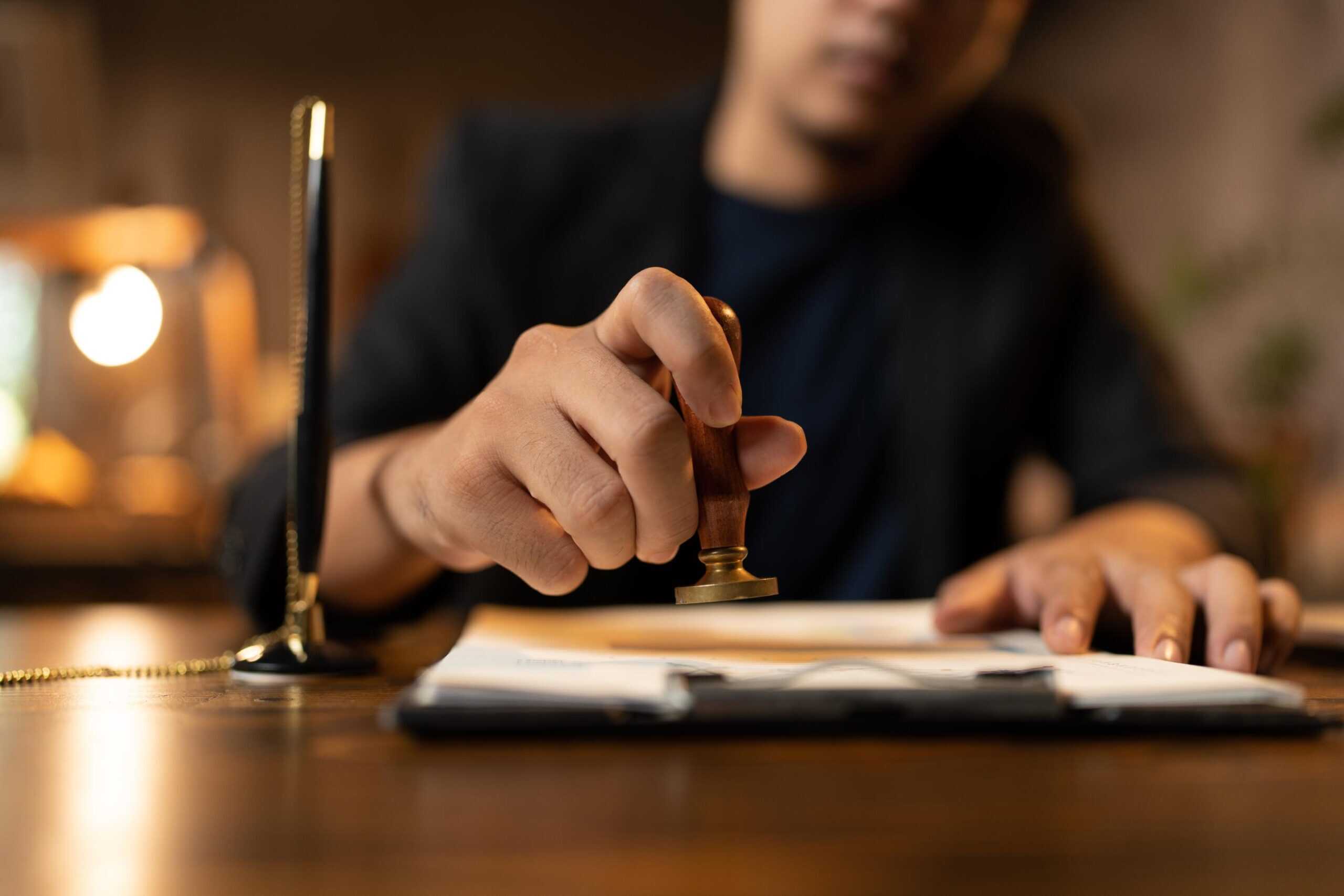 Persona estampant un segell oficial sobre documentació, representant els tràmits judicials per obtenir mesures de suport legal davant una incapacitat.