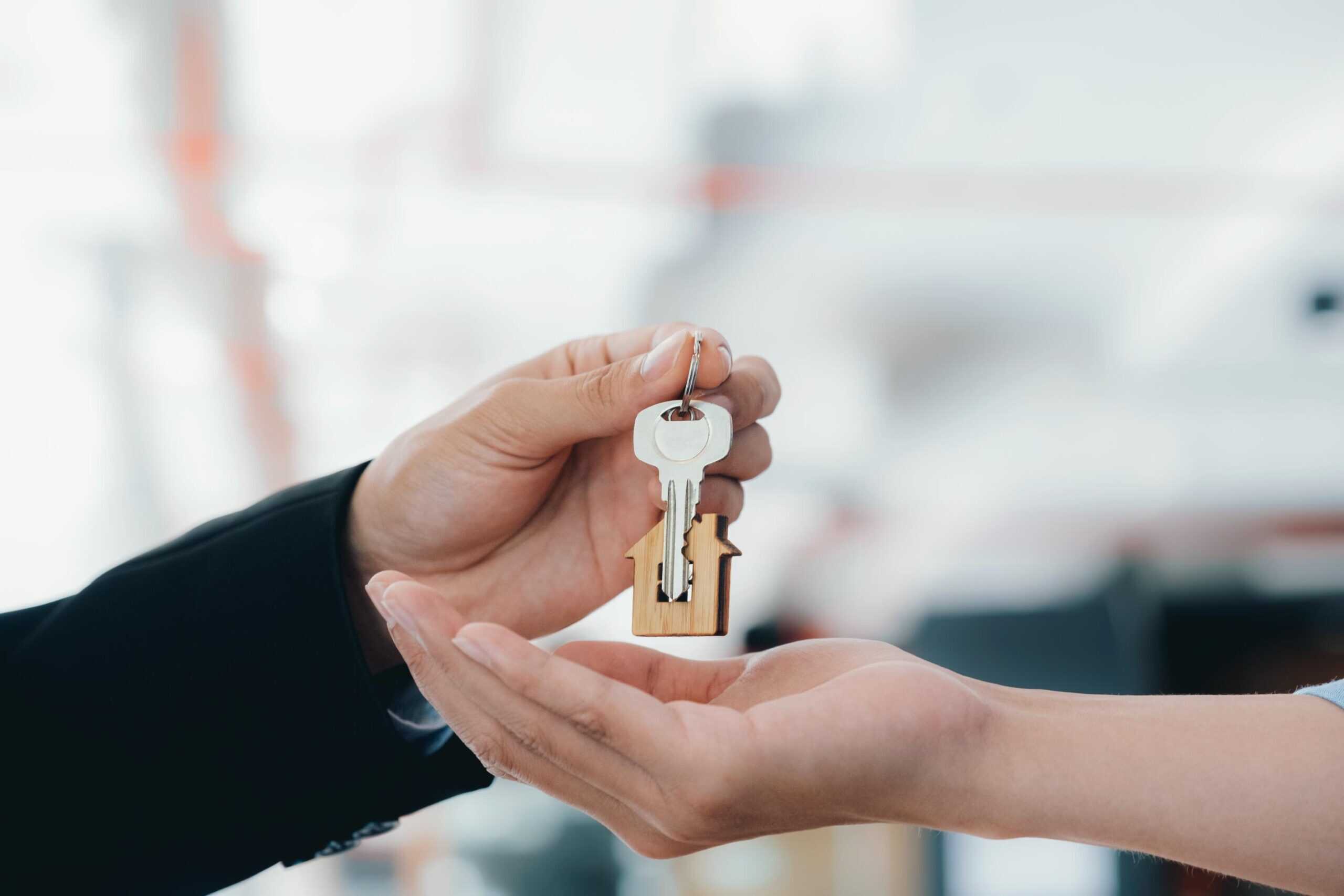 Clau de propietat amb forma de casa, representant serveis immobiliaris i legals, en una transacció immobiliària professional.